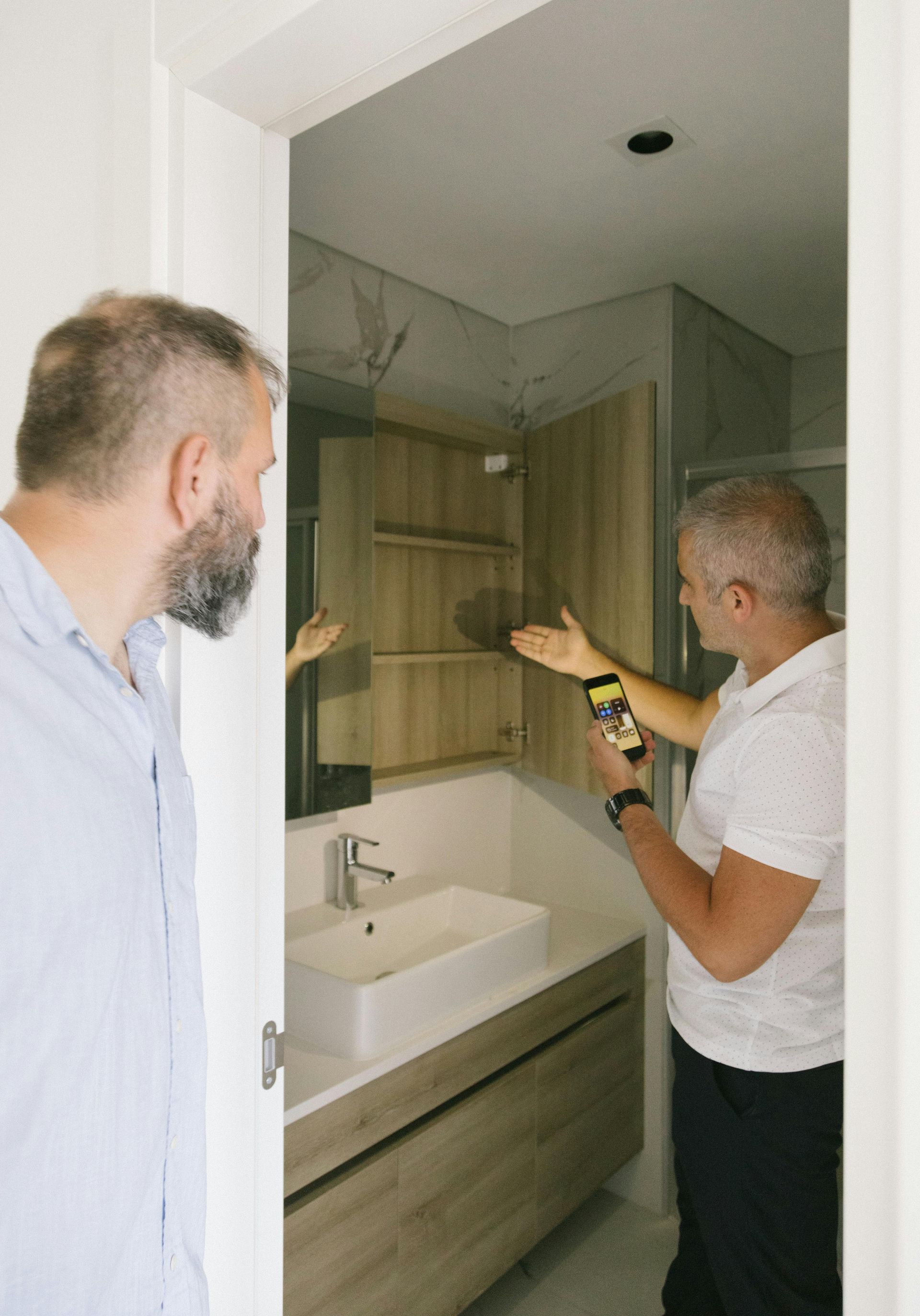 Two men examining a modern bathroom.