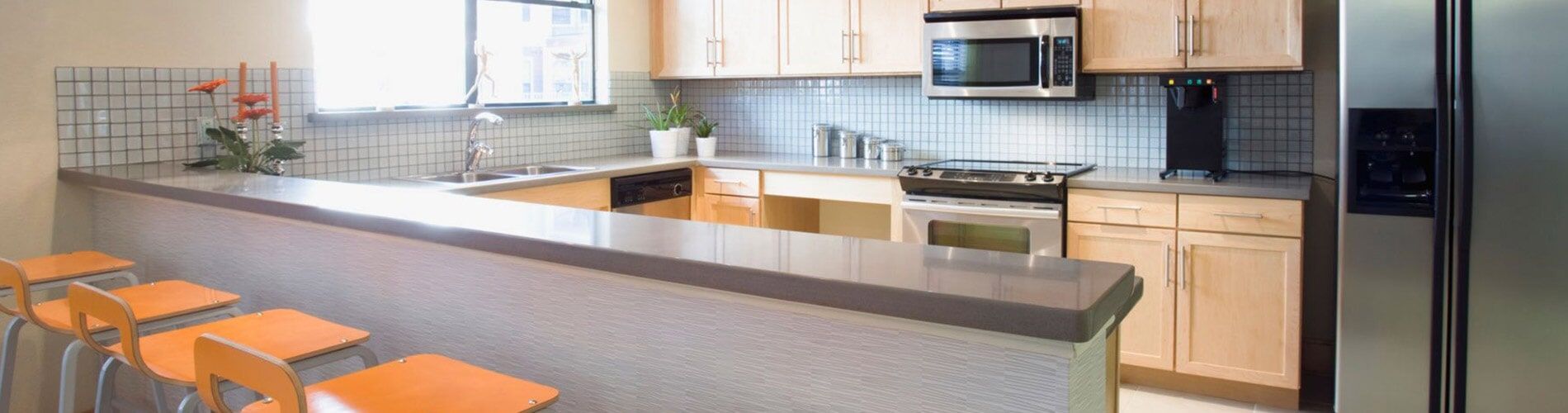 A kitchen with a stainless steel refrigerator and stools