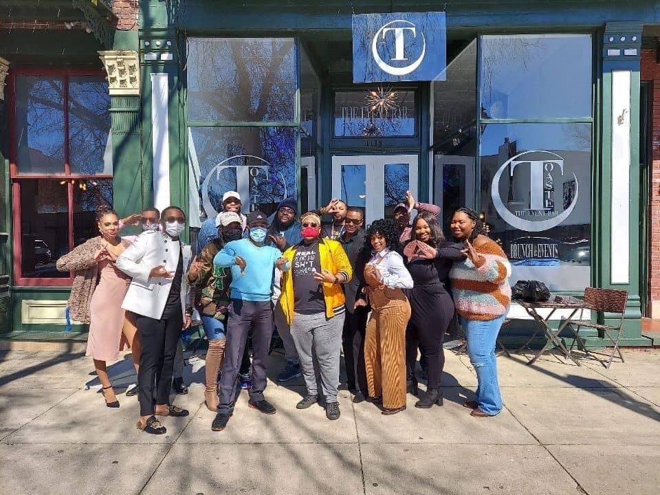 A group of people pose in front of a building with a blue 