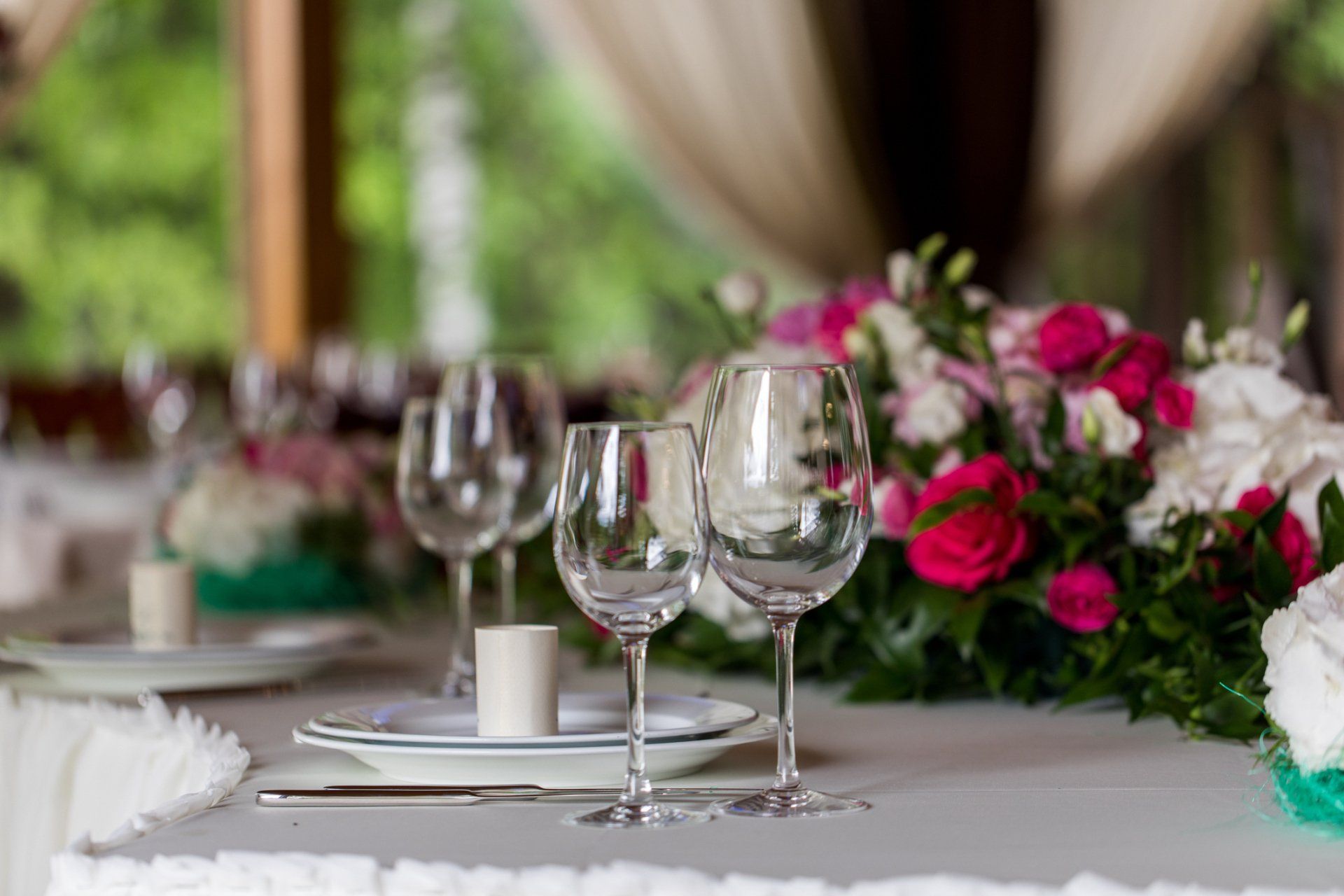 A table set for a celebration with wine glasses, floral arrangements, and a white tablecloth.