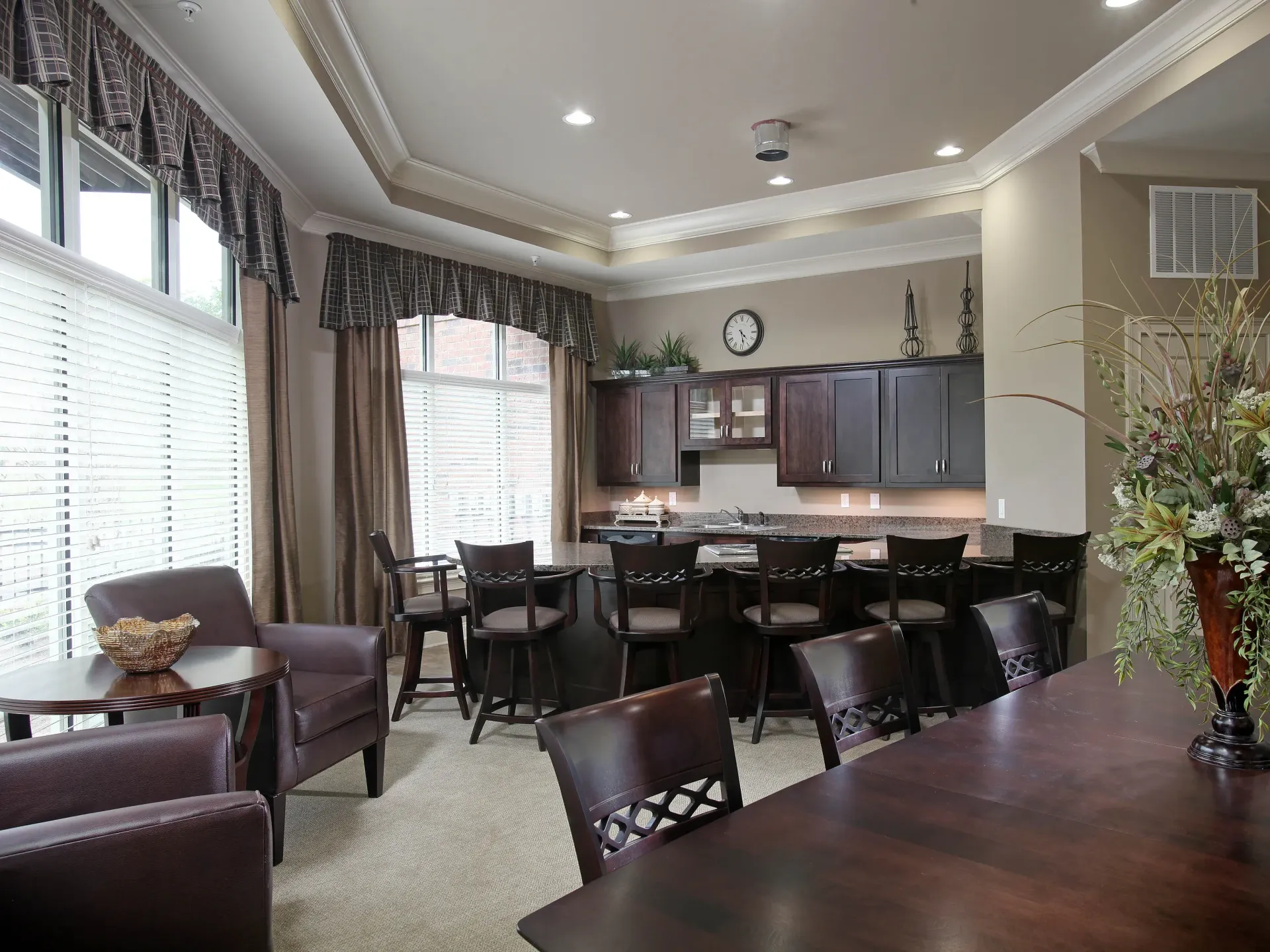 Common lounge area with dark wood kitchen cabinets, bar counter, and seating.