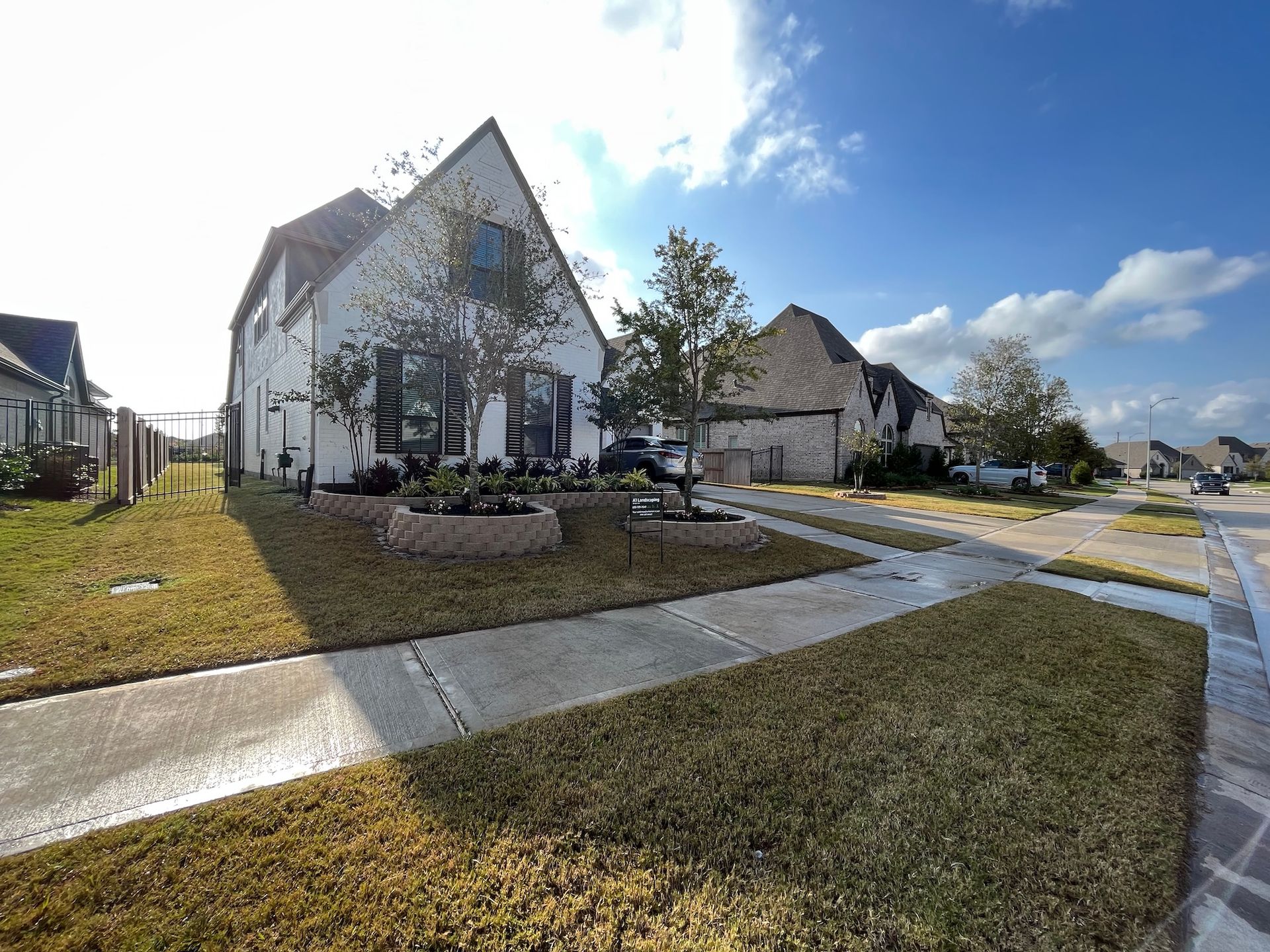 Suburban house with a brown yard, a cloudy blue sky, and a sidewalk.