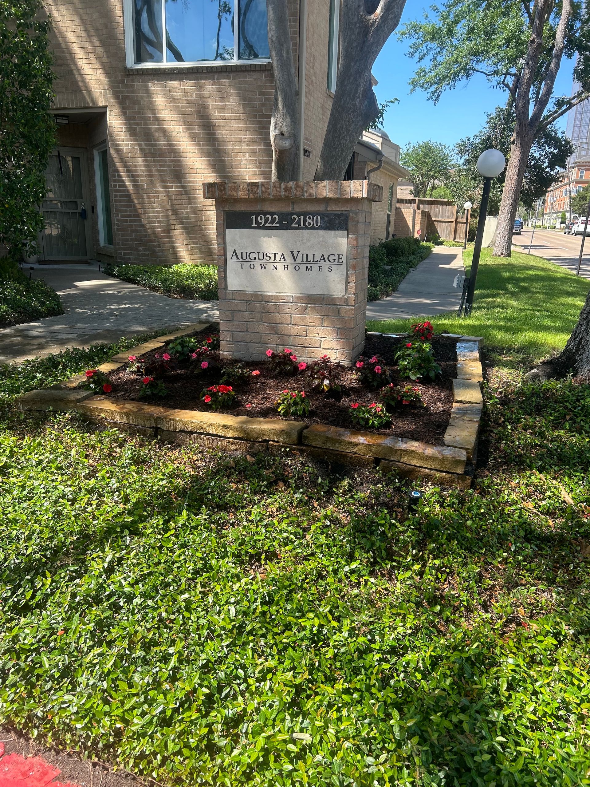 Building sign with address, surrounded by flowers and greenery.