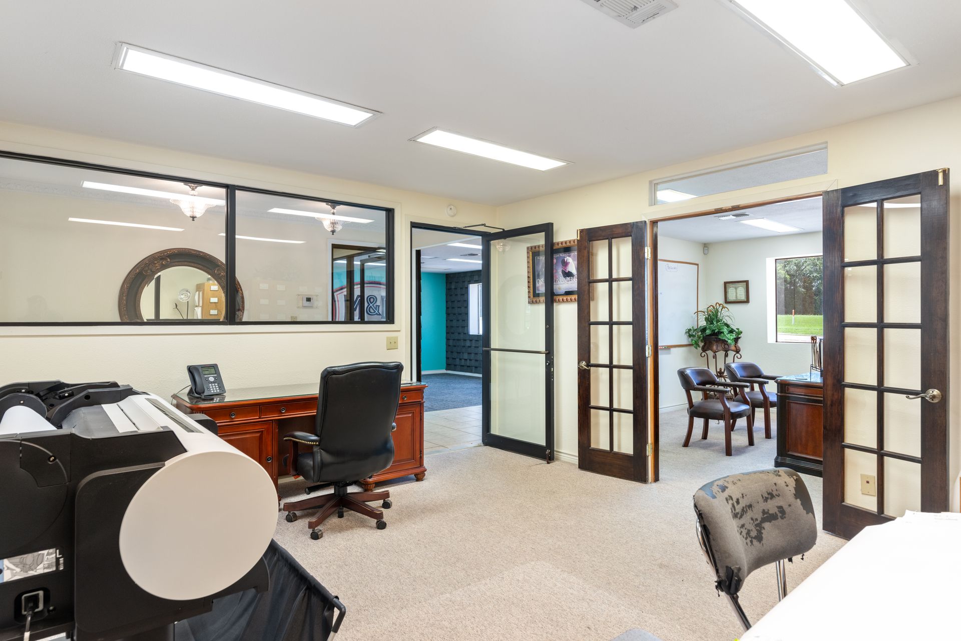 Bright office interior with desks, chairs, glass doors, and fluorescent lighting