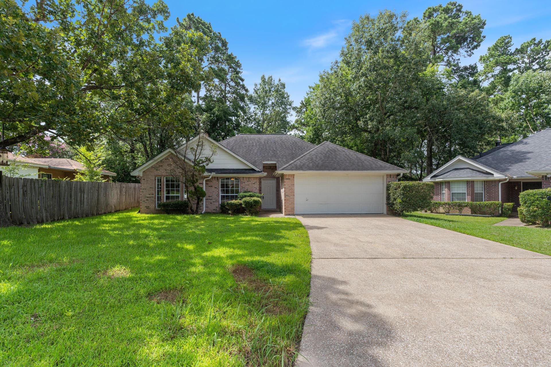 Suburban house with two-car garage, green lawn, and curved driveway under a sunny sky