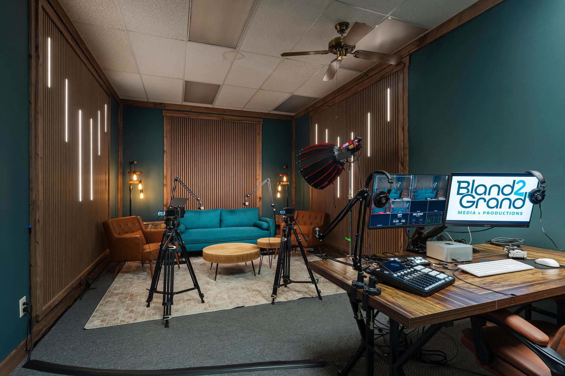 Recording studio with couches, microphones, tripods, and a computer monitor displaying a “Blood Grown” logo