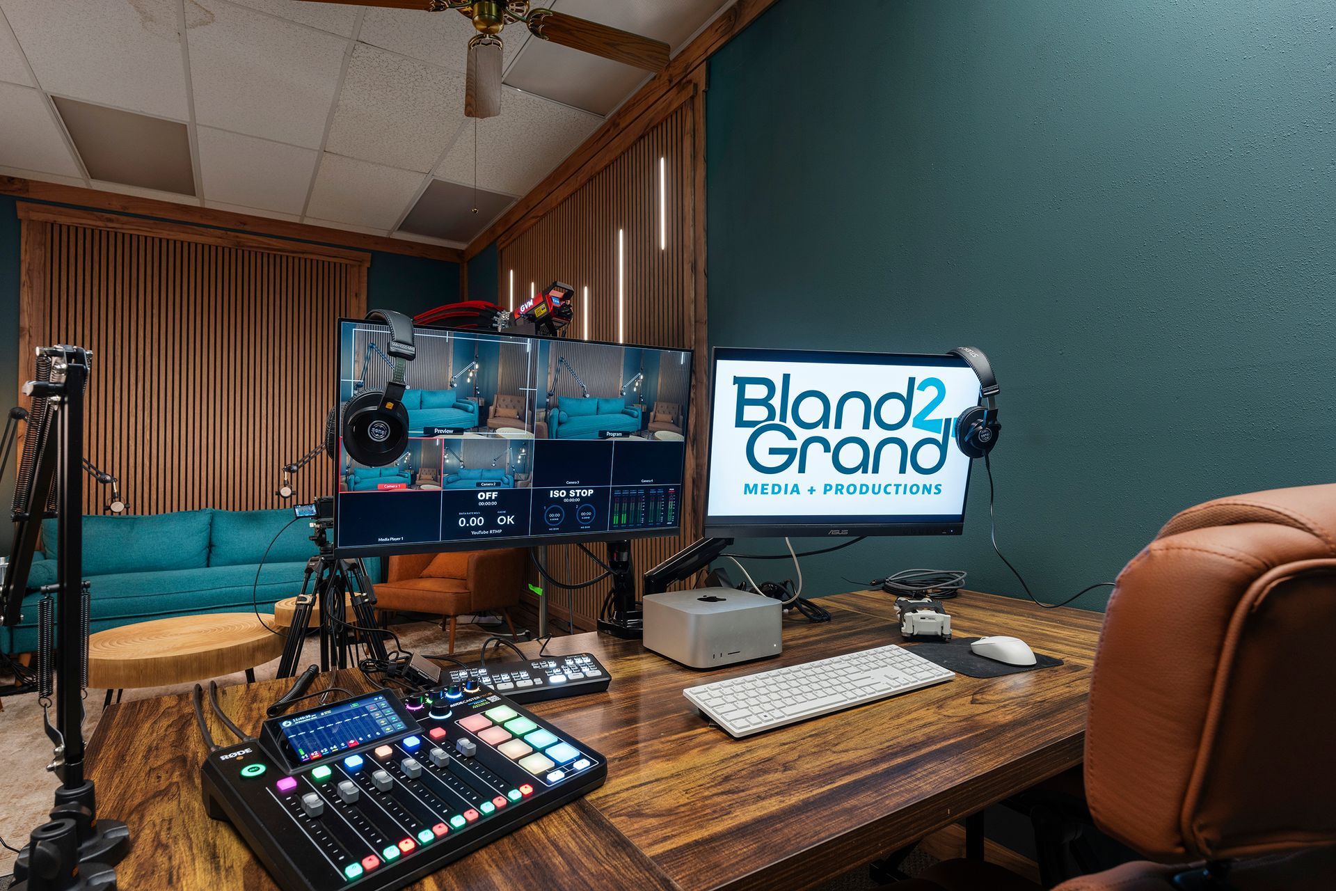 Podcast studio desk with microphones, mixer, and monitor showing “Bland2Grand”