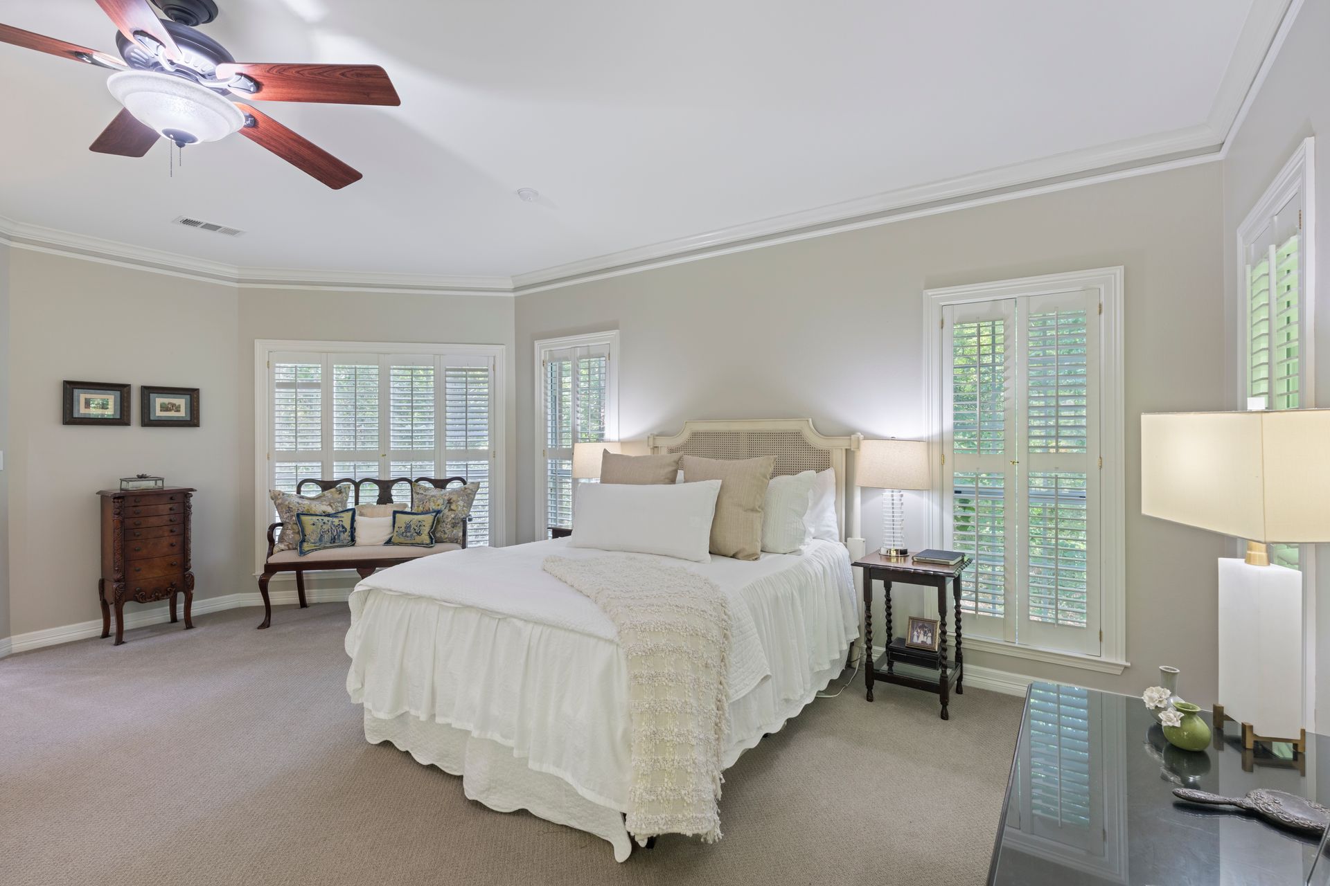 Bright bedroom with a white bed, ceiling fan, nightstands, and French doors to a balcony
