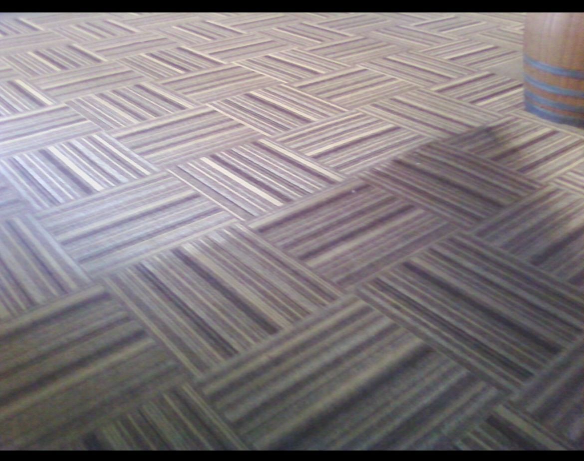 A close up of a carpeted floor with a herringbone pattern