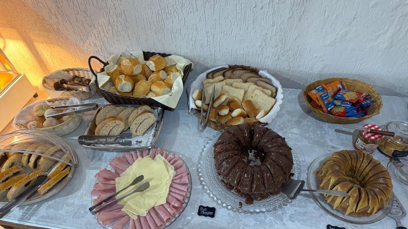 Variedade de doces e biscoitos dispostos em bandejas numa mesa de bufê.