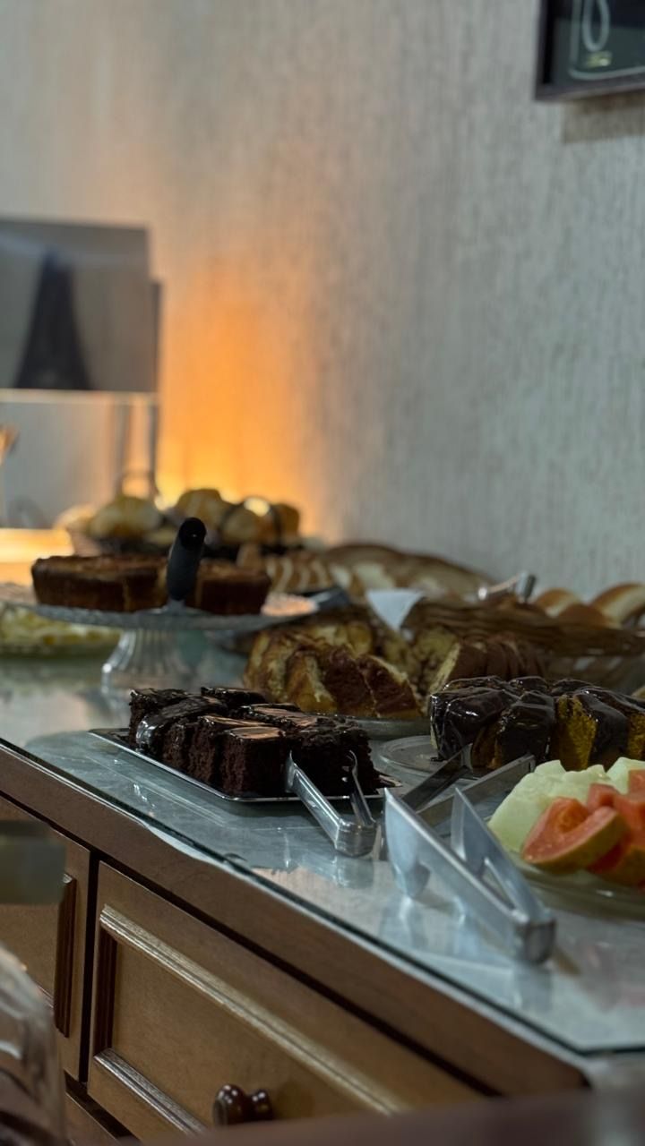 Mesa de buffet com uma variedade de doces e sobremesas sob uma iluminação ambiente aconchegante.