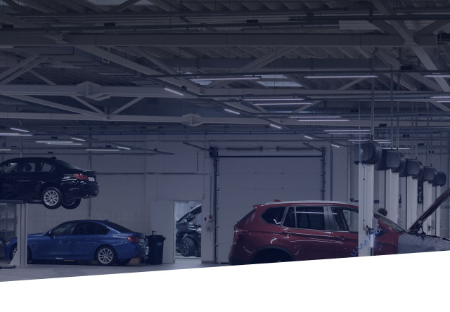 Two cars are sitting on a lift in a garage. | Greatway Tire and Auto Center