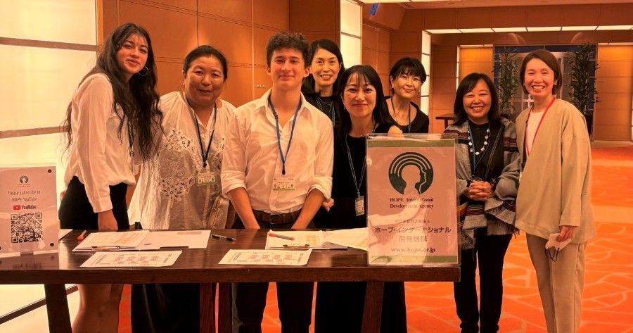 Group of people smiling at a registration table. Sign says