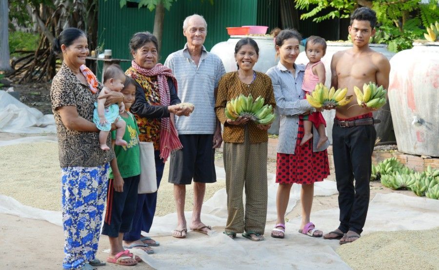 People standing outdoors holding baskets of harvested produce on a garden path