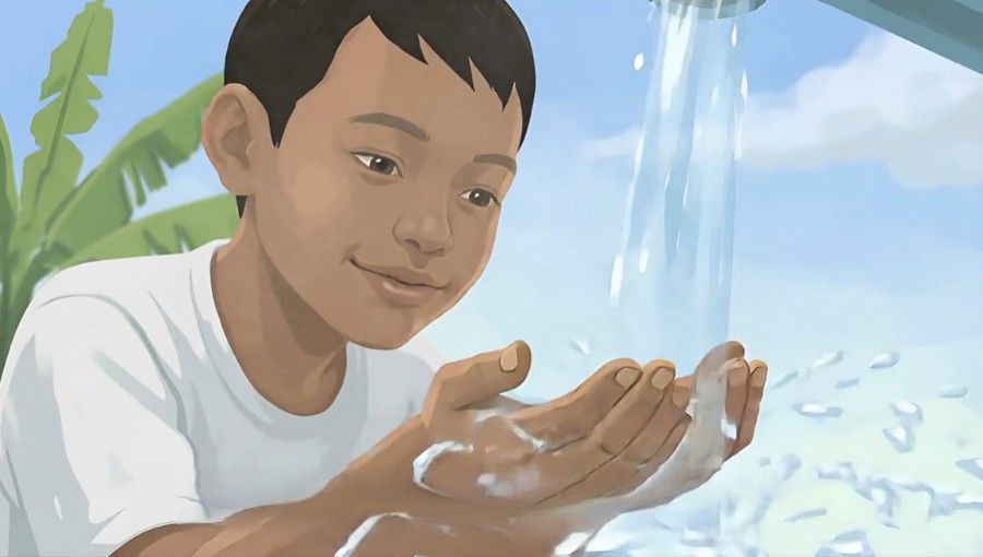 Child washing hands under running water outdoors, with a plant in the background