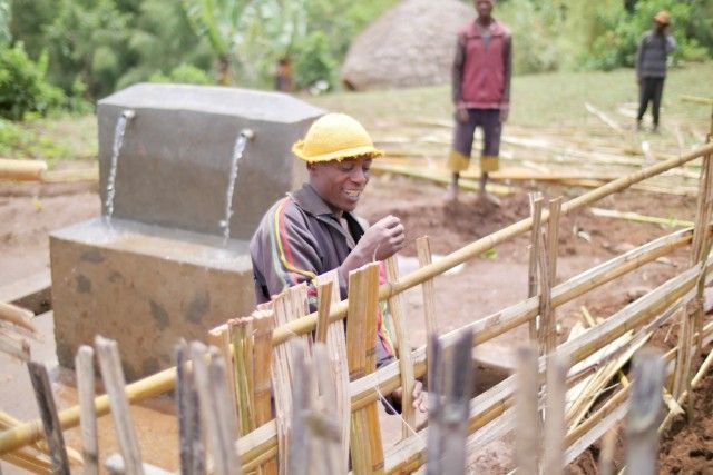 Construction worker in yellow hard hat near a concrete structure and wooden scaffolding outdoors