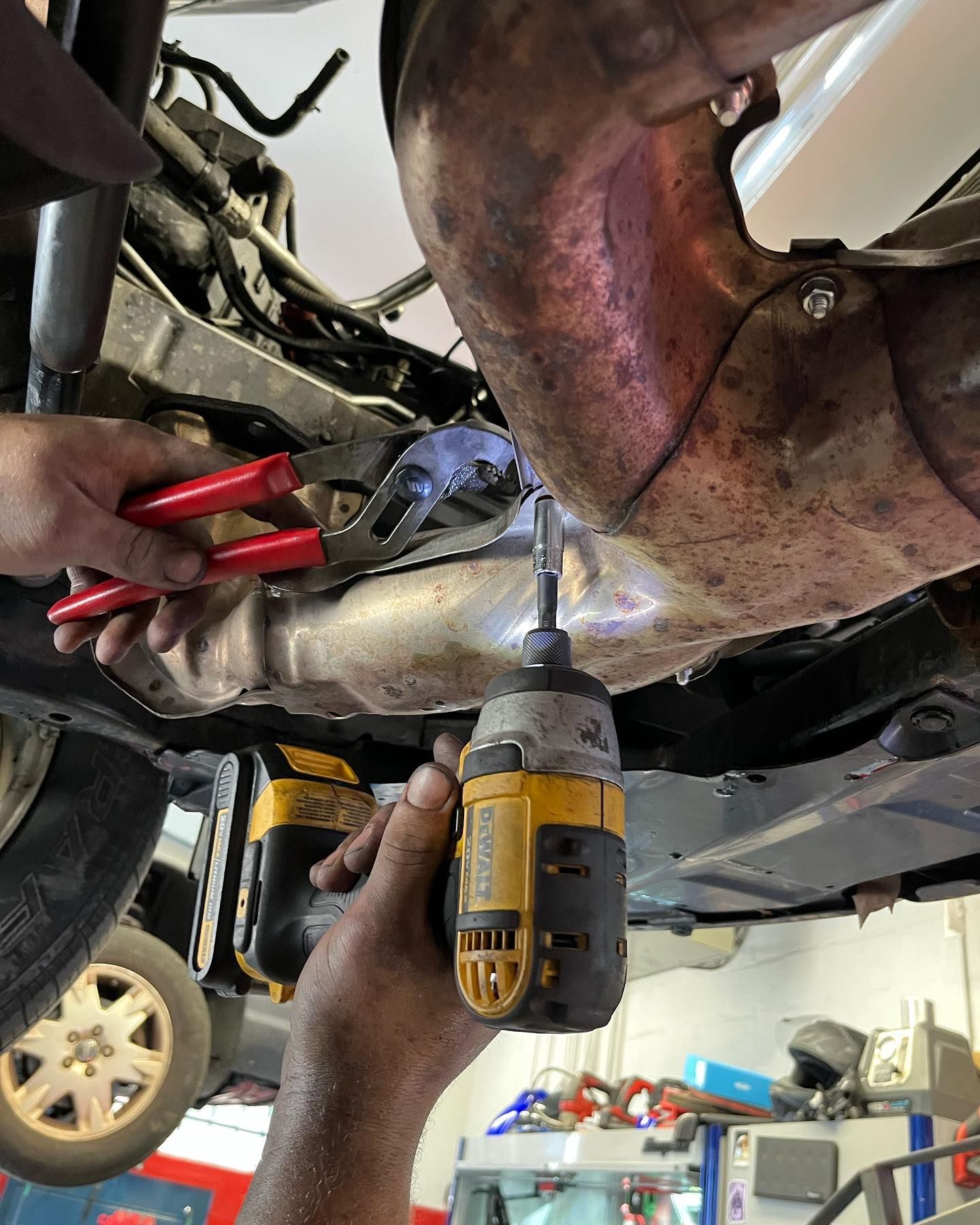 Mechanic Working Under Vehicle Exhaust System Inside Garage | East Rock Auto Repair