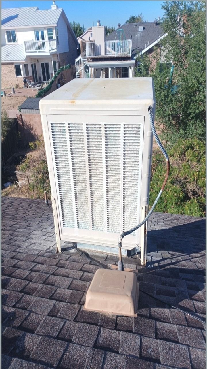 White rooftop HVAC unit on shingled roof in a suburban neighborhood