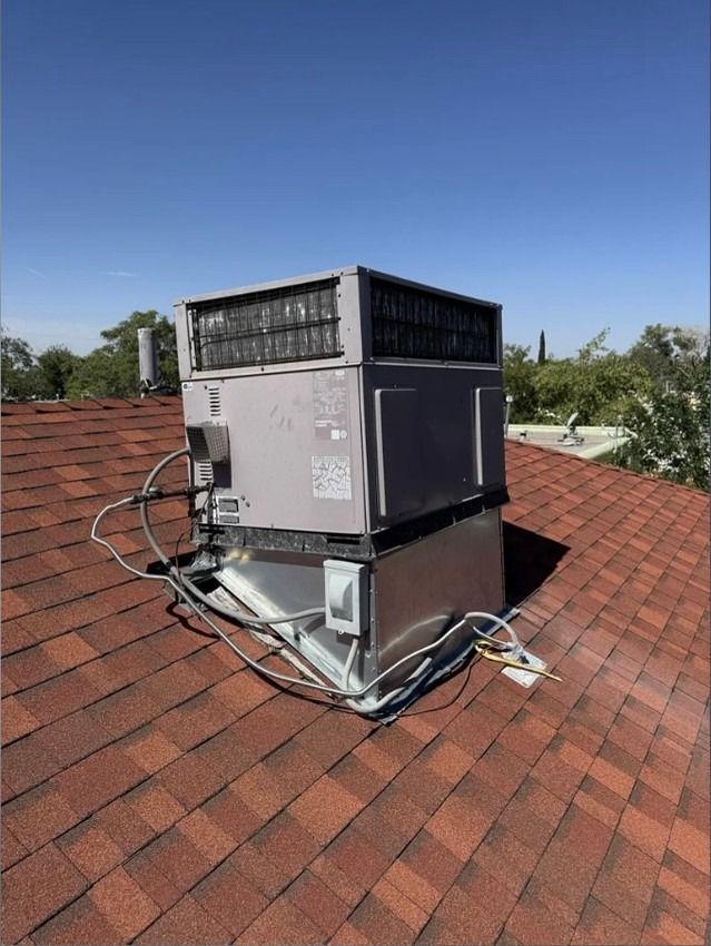 HVAC unit on a red shingle rooftop under a clear blue sky