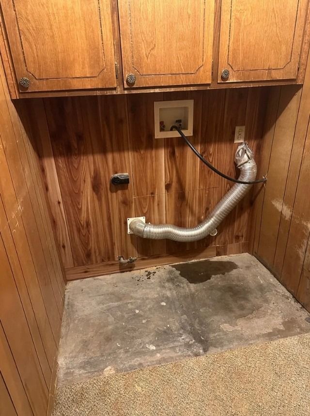 Laundry nook with wood cabinets, exposed plumbing, and a concrete floor under a utility sink area