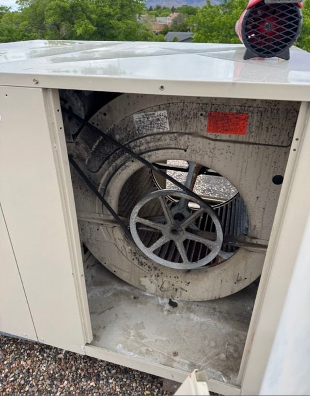 Open HVAC unit with large fan and wiring visible, outdoors on a rooftop.