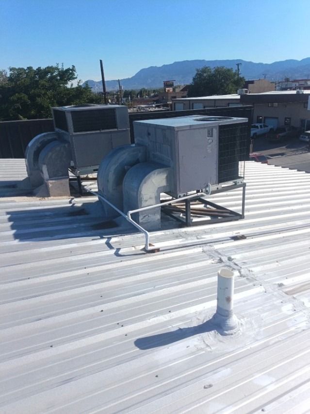 Rooftop HVAC units and vents on a white metal roof with mountains in the background