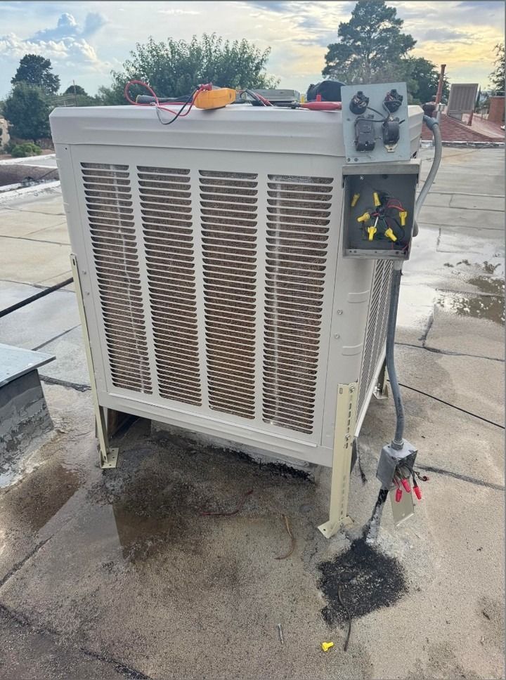 Old rooftop HVAC unit with control box and pipes, on a wet concrete surface