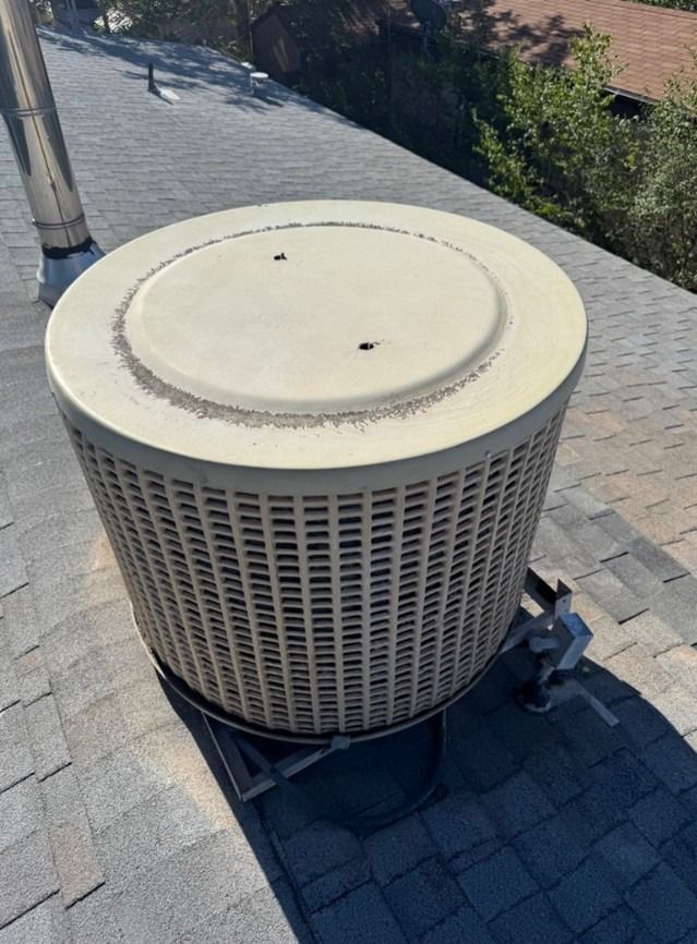 Rooftop HVAC unit with a beige circular top on gray shingles, viewed from above.