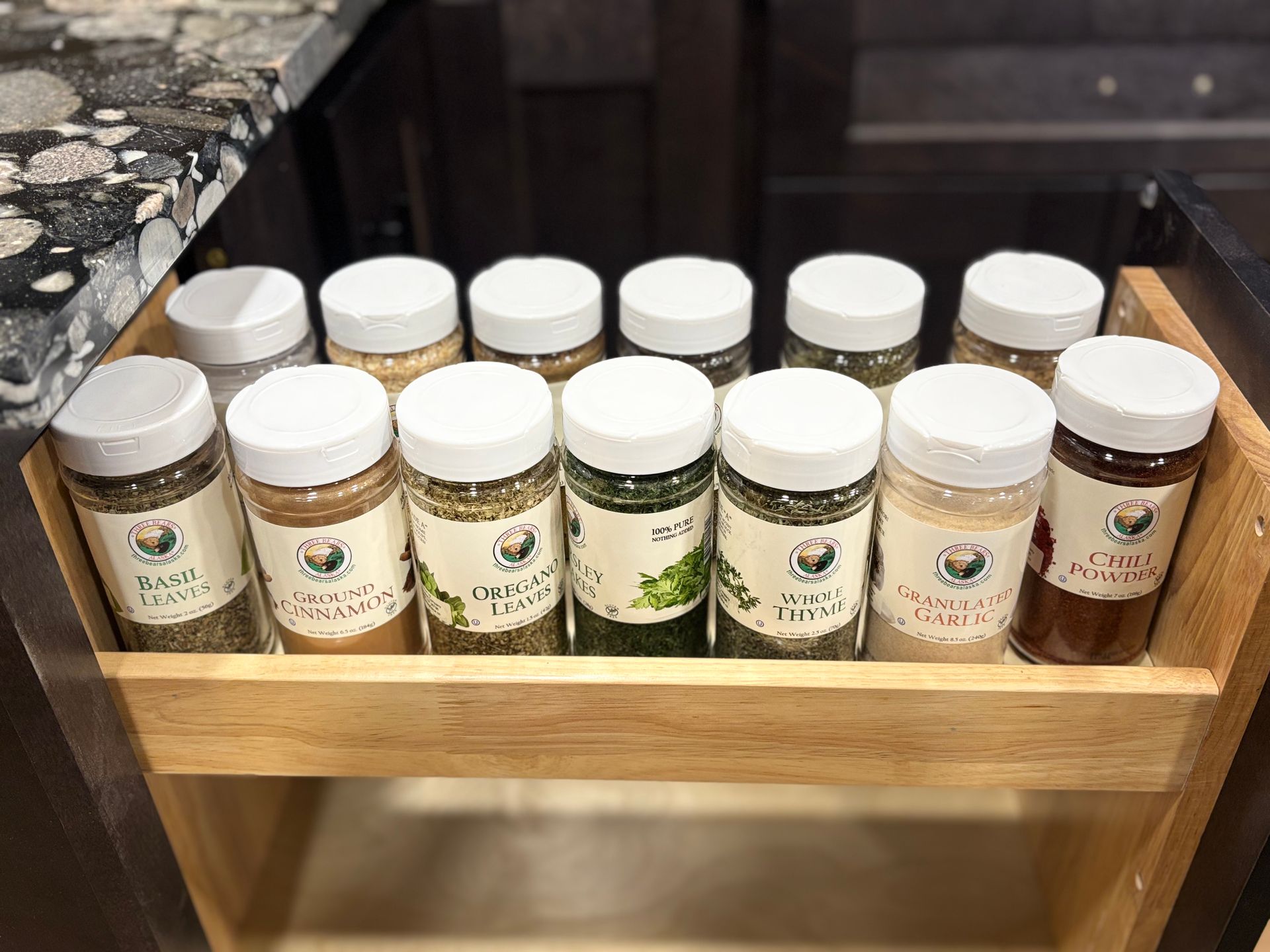 Wooden spice rack with jars of herbs and seasonings on a kitchen counter