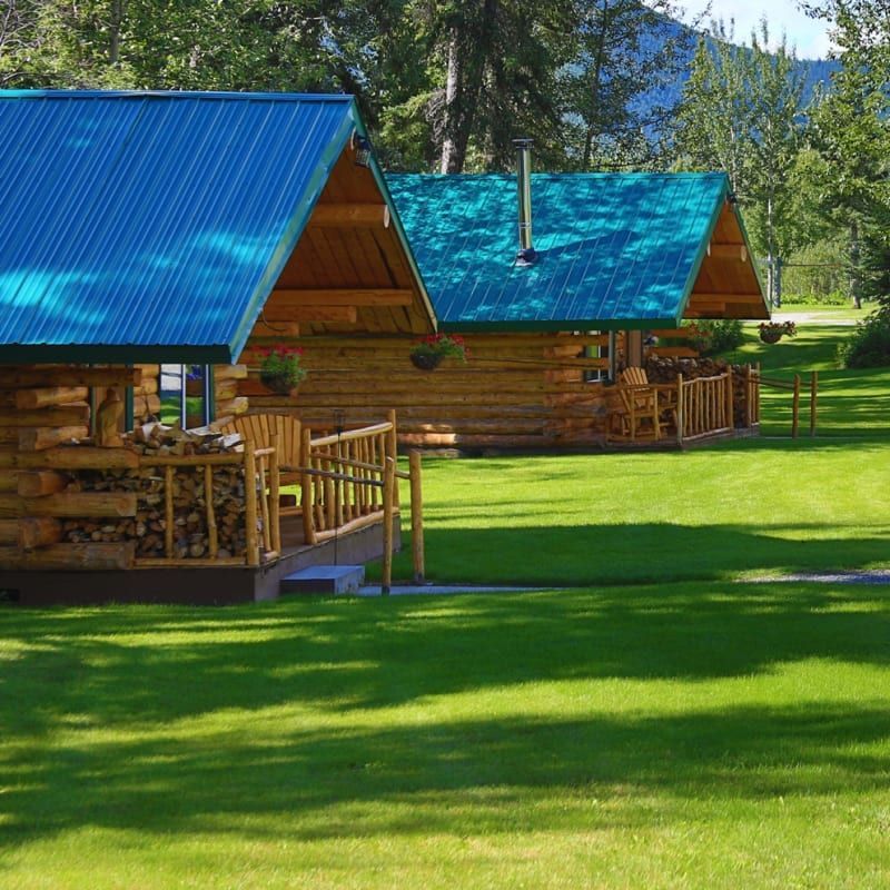 Two log cabins with blue roofs in a grassy area