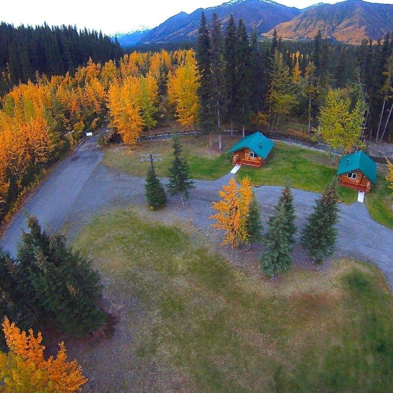 An aerial view of a cabin in the woods with mountains in the background