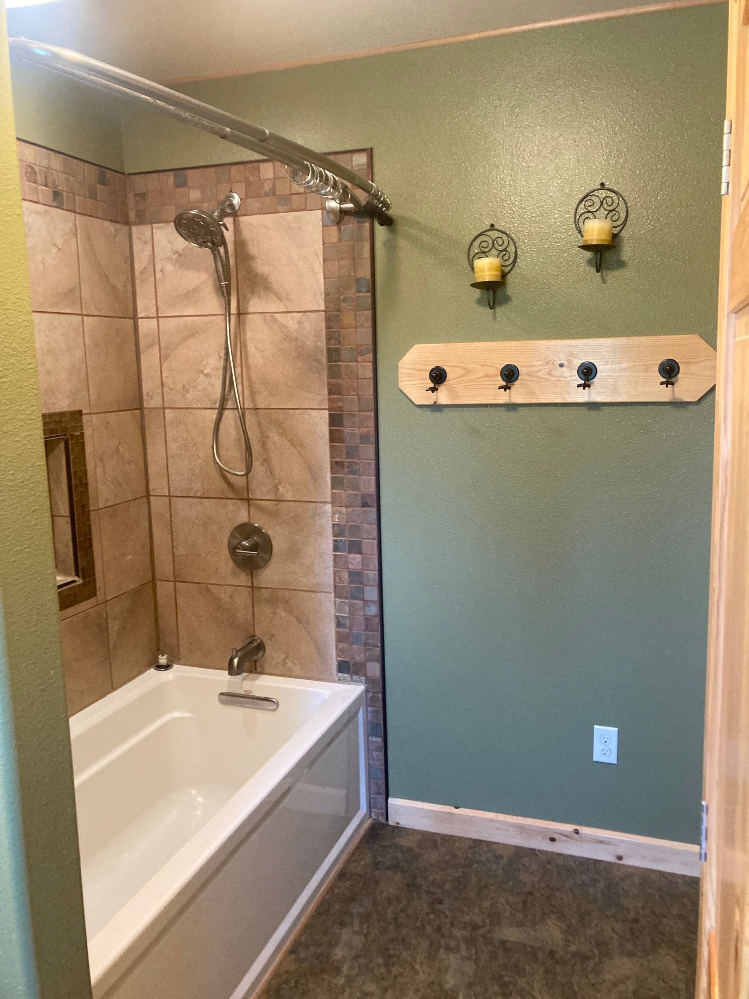 Bathroom with a white tub, shower with tan tile, and green walls.