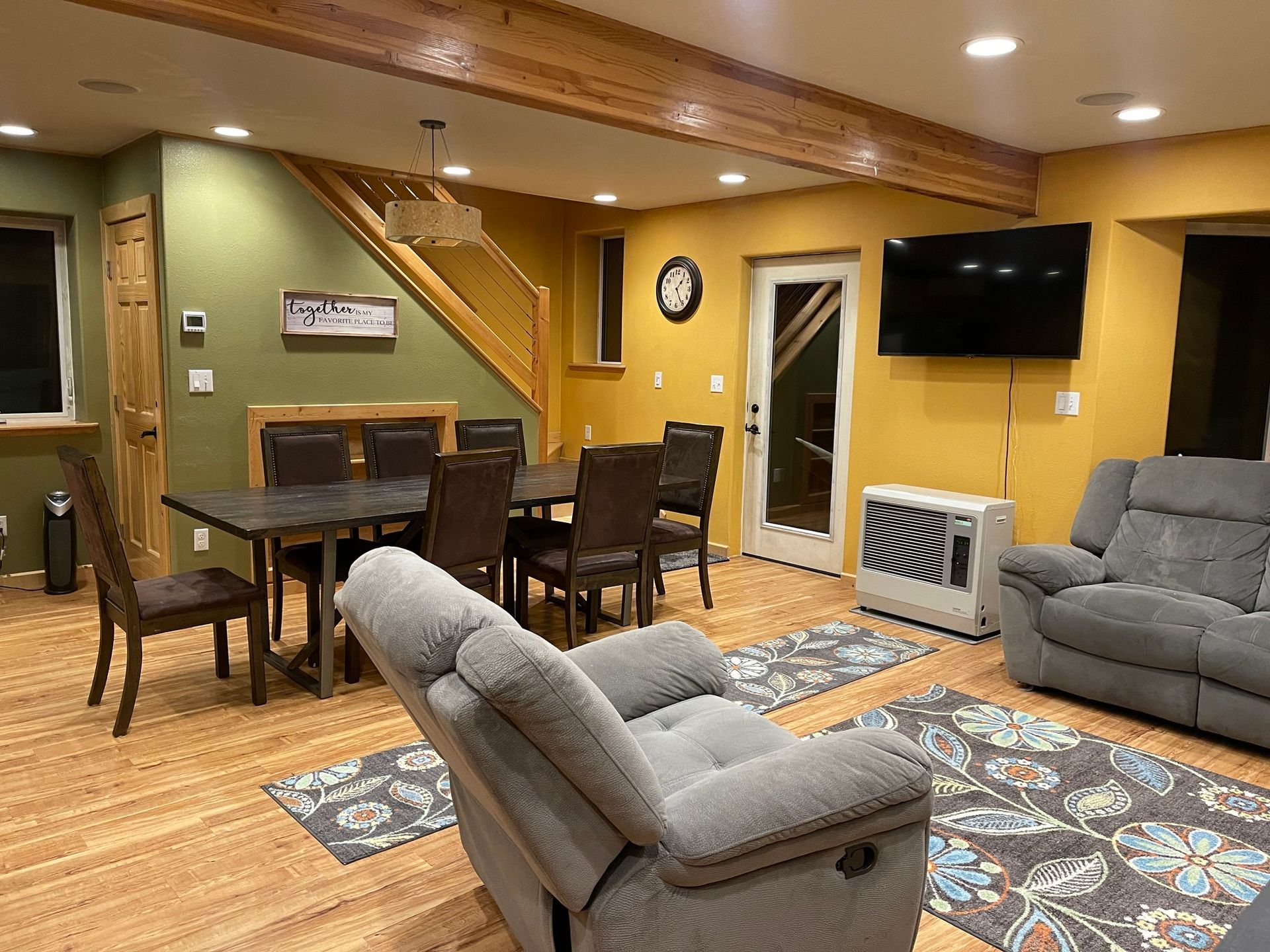 Living room with dining area, gray recliners, wooden floor, and yellow and green walls.