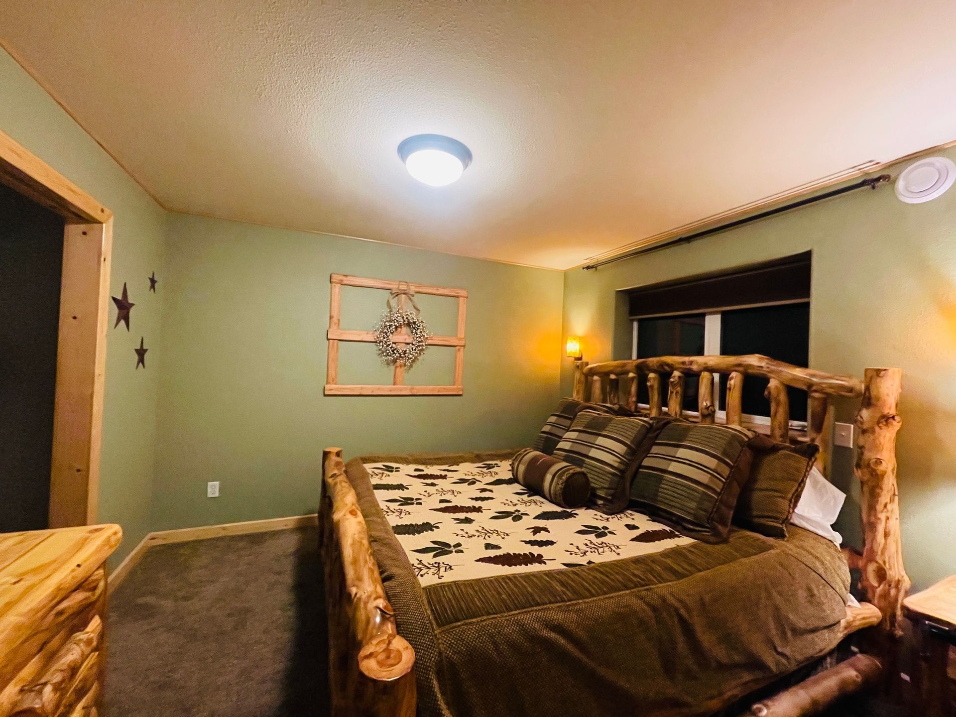 Rustic bedroom with a wooden bed frame, green walls, and star decor.