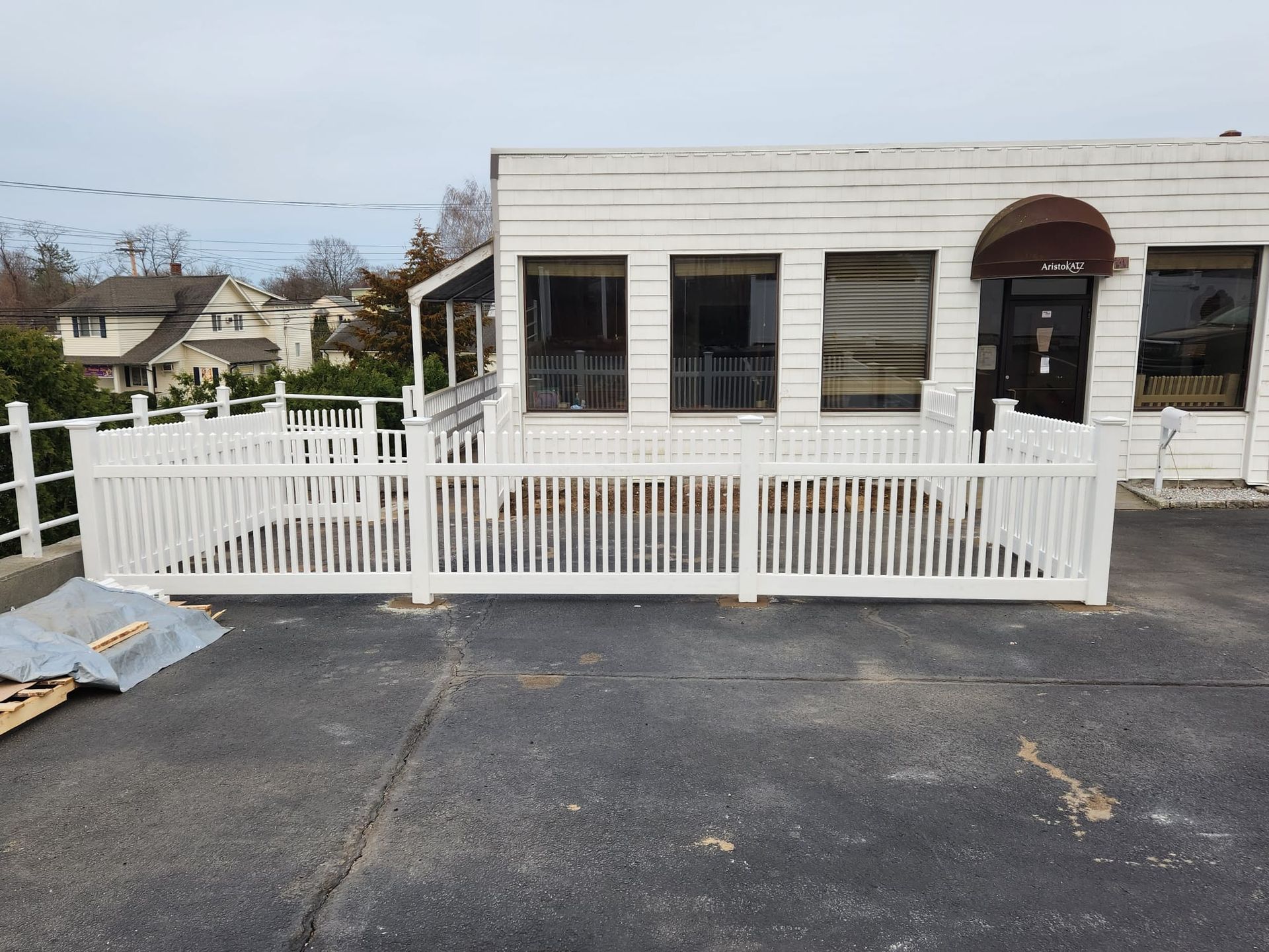 Small white building with a fenced ramp and blacktop parking area in front