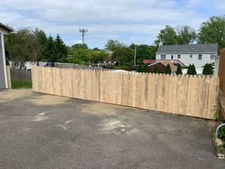 New wooden fence along an asphalt driveway in a residential yard