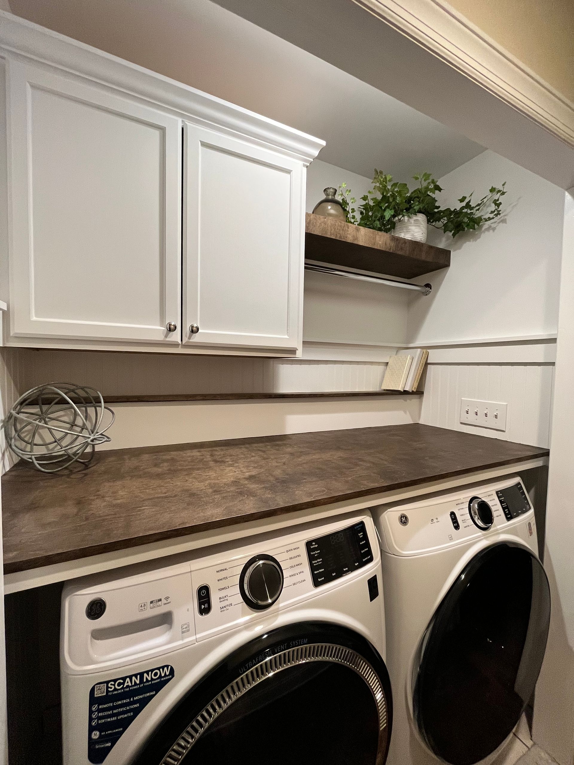 Laundry room with white cabinets, brown countertop, and a washer and dryer side by side.
