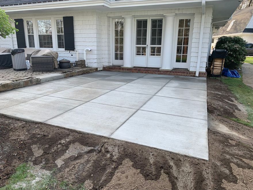 Concrete patio in front of a white house with French doors and outdoor seating