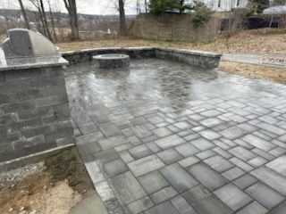 Empty stone patio with a built-in fire pit in a damp outdoor yard