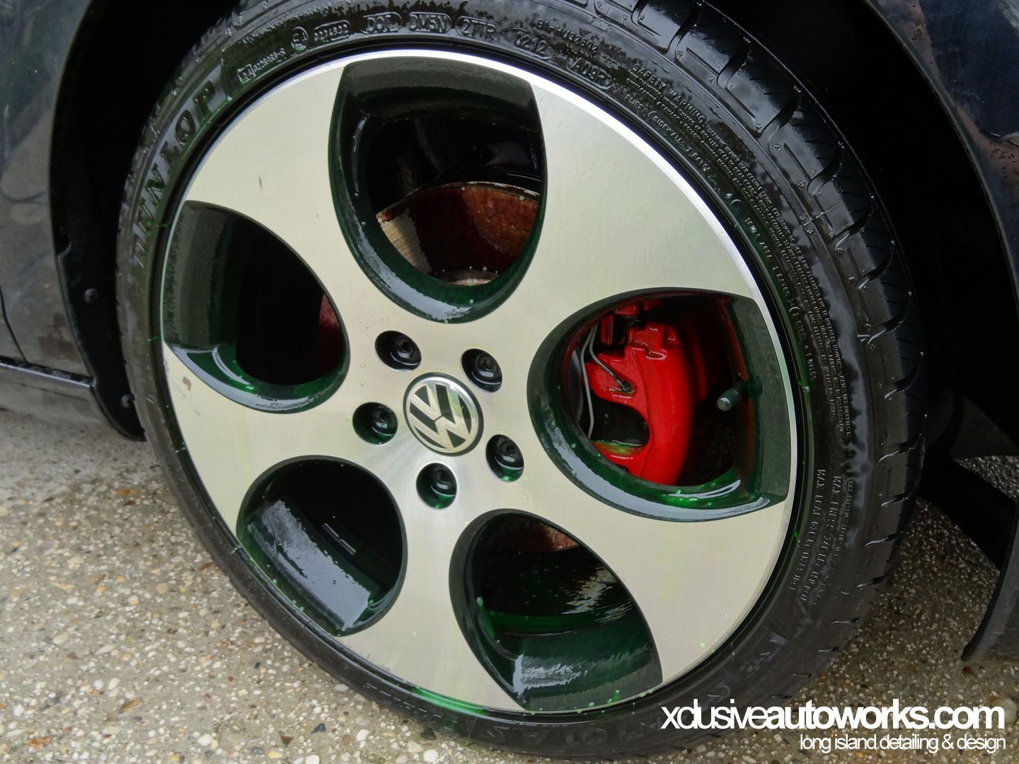 A close up of a car wheel with a red brake caliper.