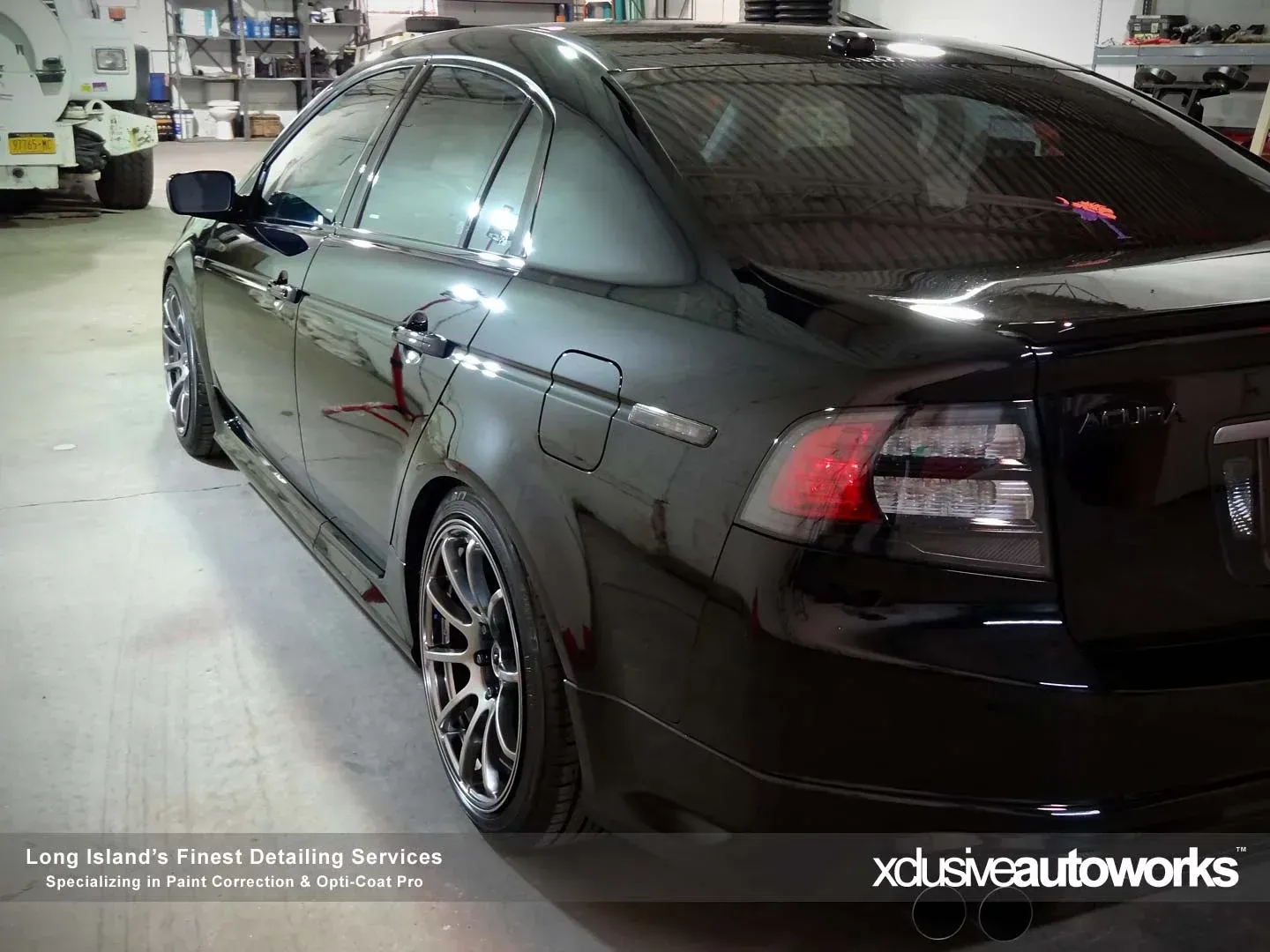 A black car is parked in a garage by xclusive autoworks