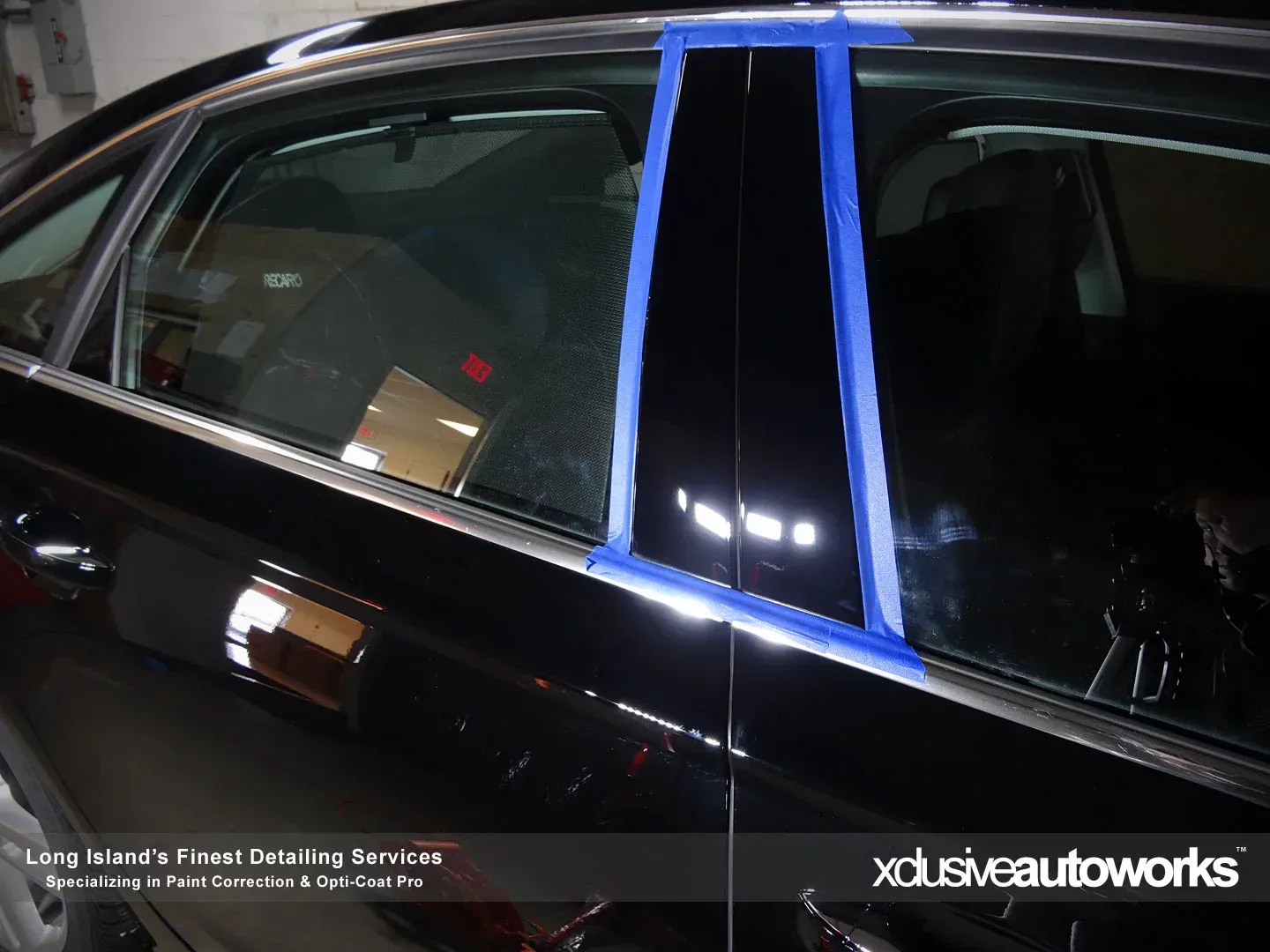 A black car with a blue tape covering the pillars