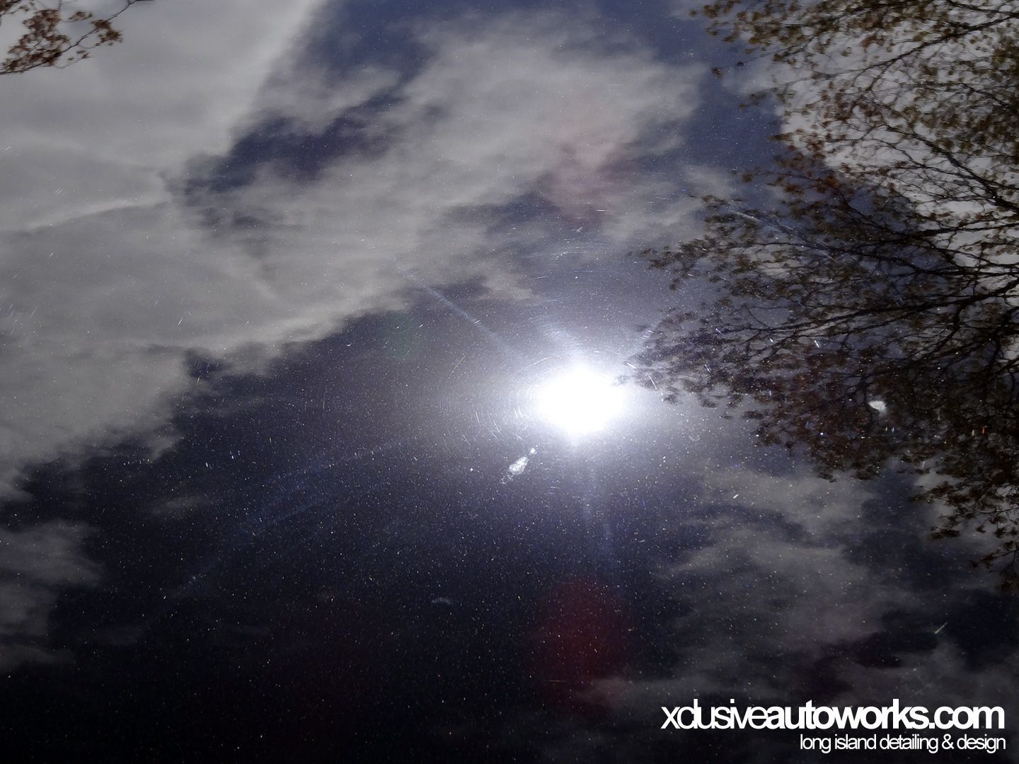 The sun is shining through the clouds and the website xdusveautoworks.com is visible