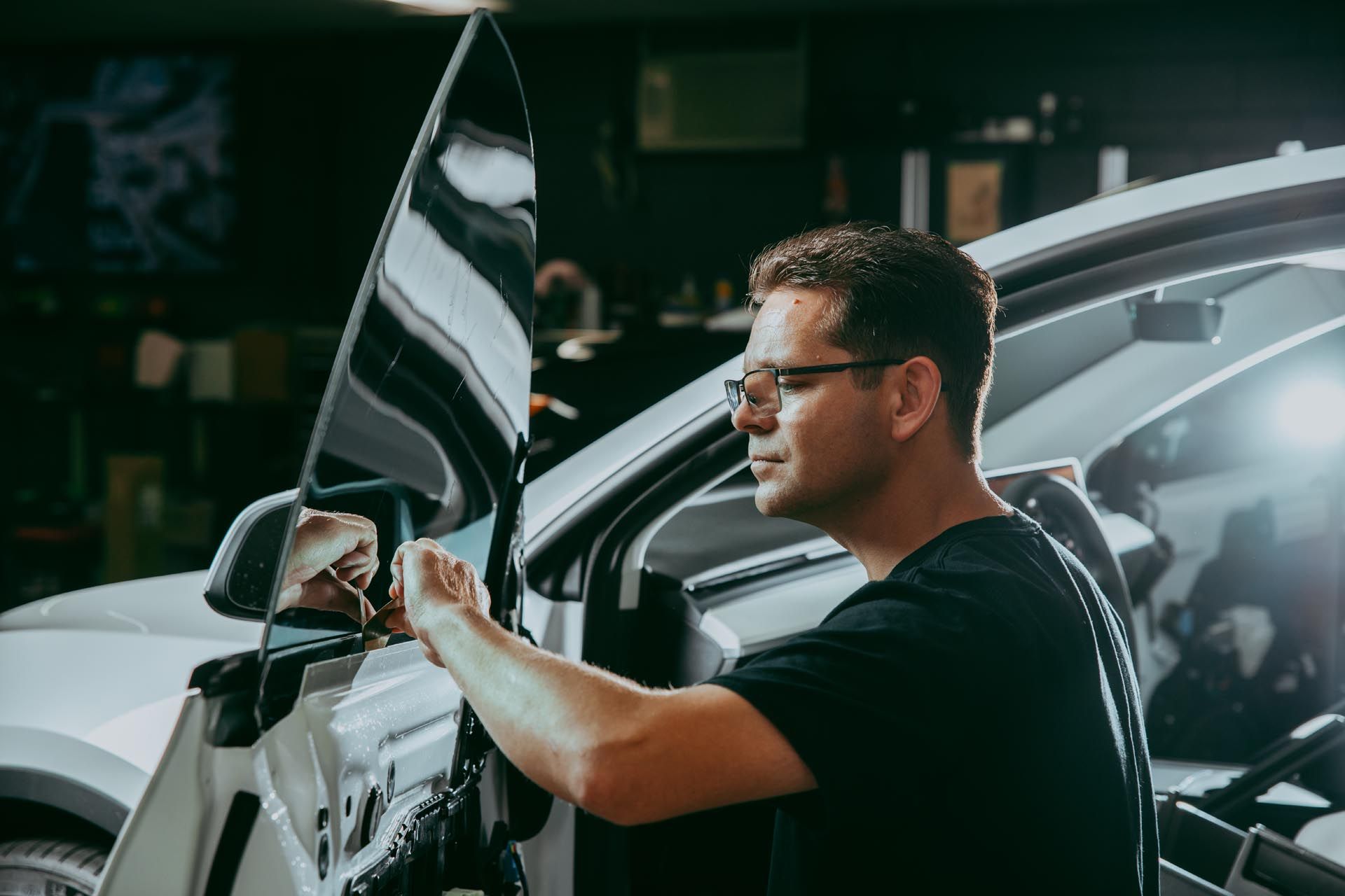 A man is installing a window tint on a car.
