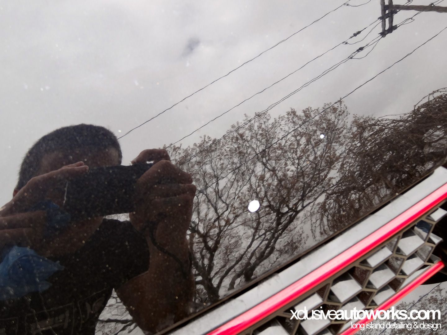 A person taking a picture of their reflection in a car window
