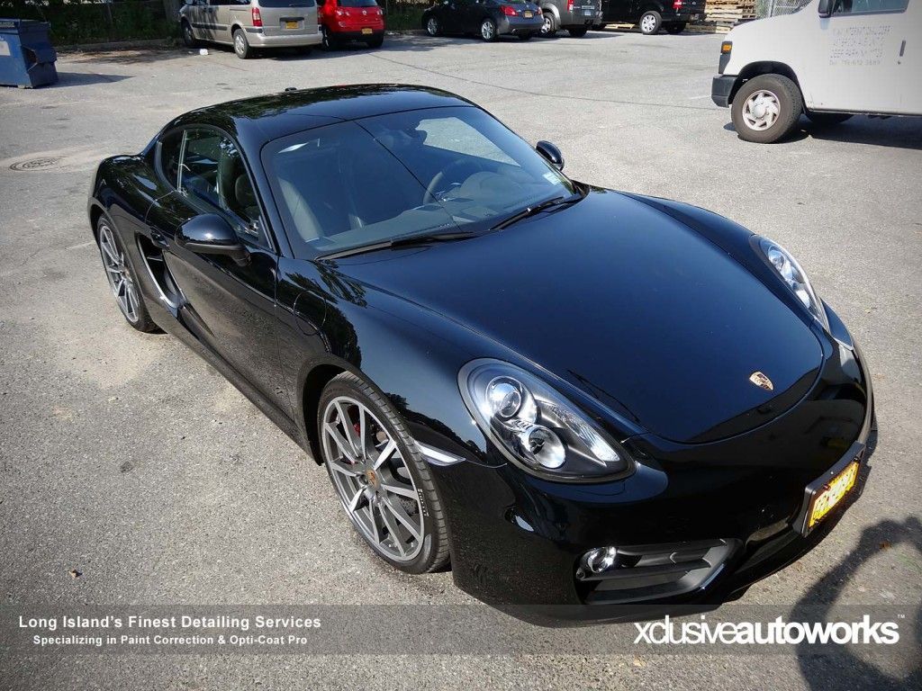 A black porsche is parked in a parking lot