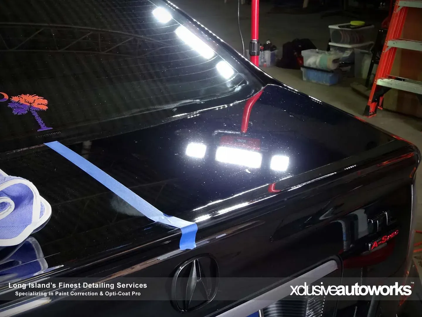 A black car is being polished by xclusive autoworks