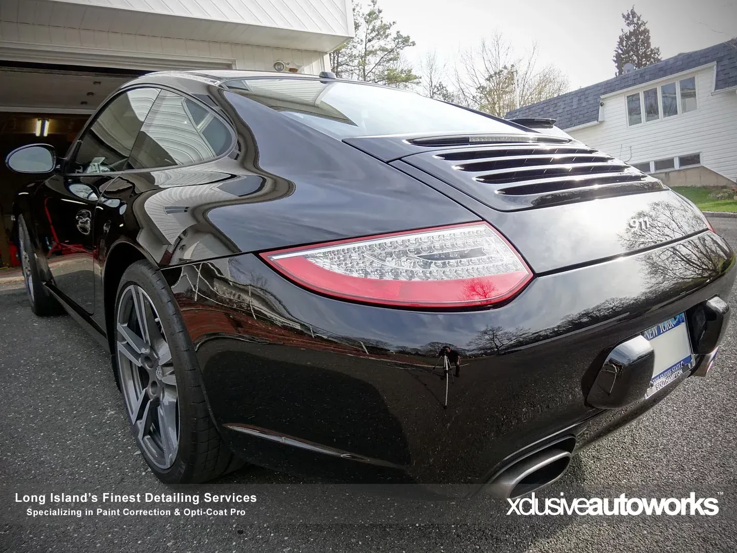 A black porsche 911 is parked in front of a garage