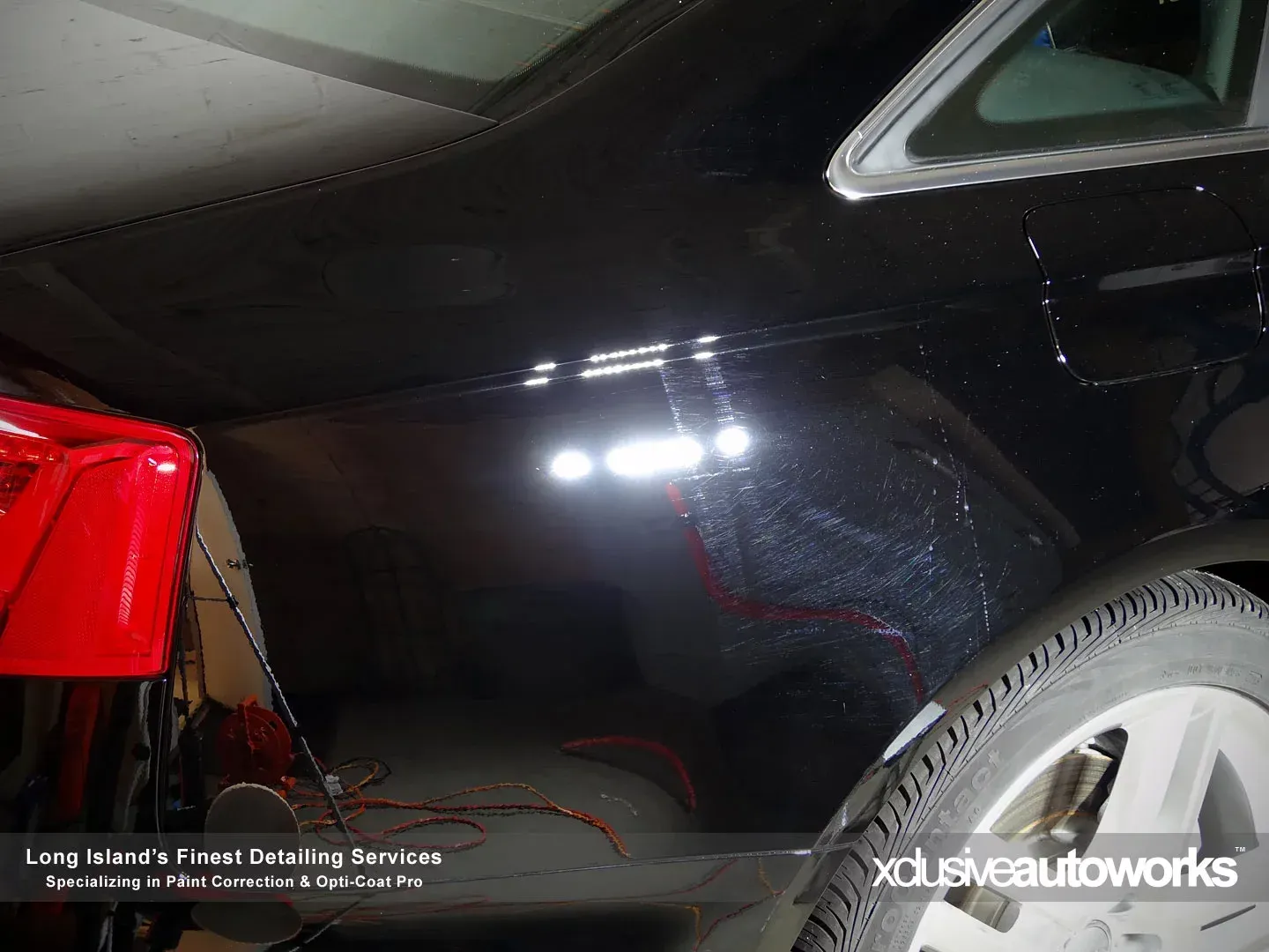 A black car is sitting in a garage next to a red car.