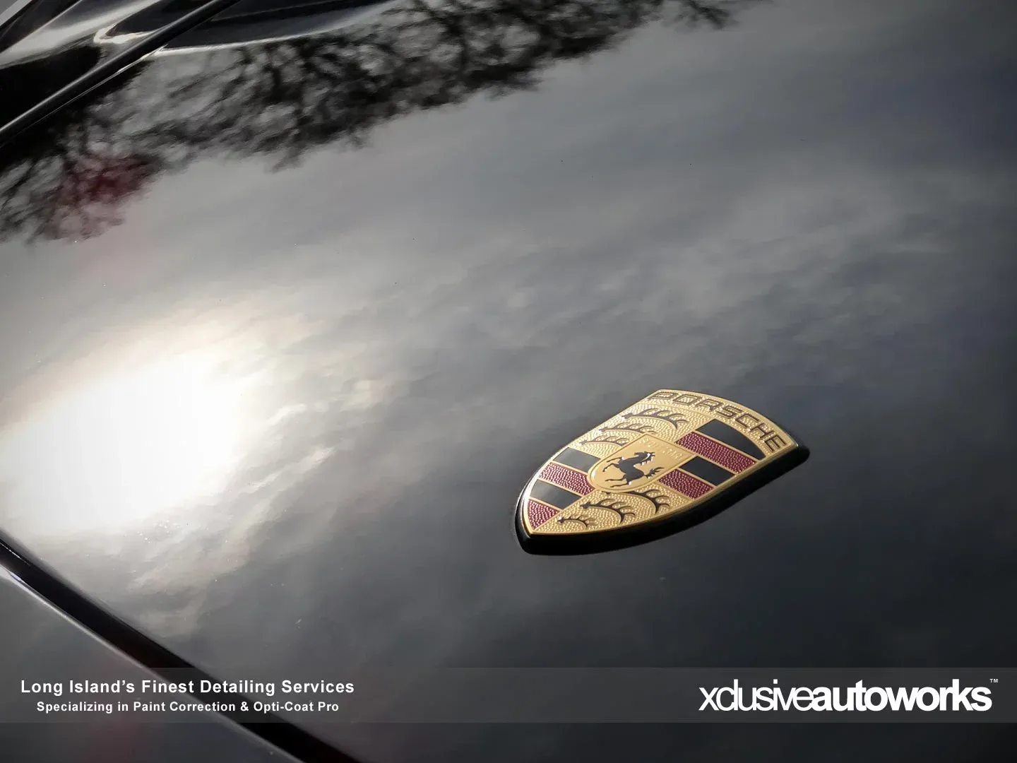 A porsche emblem is on the hood of a black car.